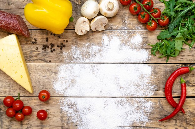 Ingredienti per fare la pizza su un tavolo di legno con spazio per testo infarinato, vista dall'alto