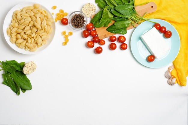 Ingredienti per formaggio feta al forno con pomodori e pasta, aglio pepe su una vista dall'alto di sfondo chiaro.