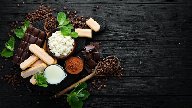 Ingredienti per il dessert al tiramisù Vista dall'alto su un tavolo di legno nero Spazio libero per il testo