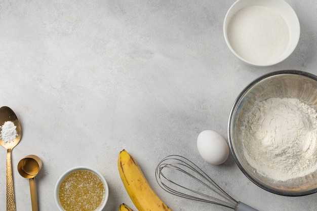 Ingredienti per il pane alla banana in ciotole su sfondo grigio chiaro vista dall'alto