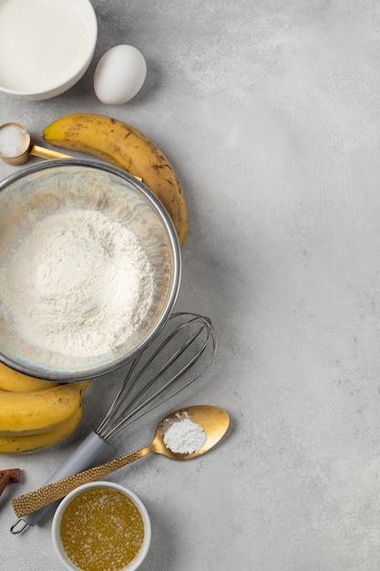 Ingredienti per il pane alla banana in ciotole su sfondo grigio chiaro vista dall'alto