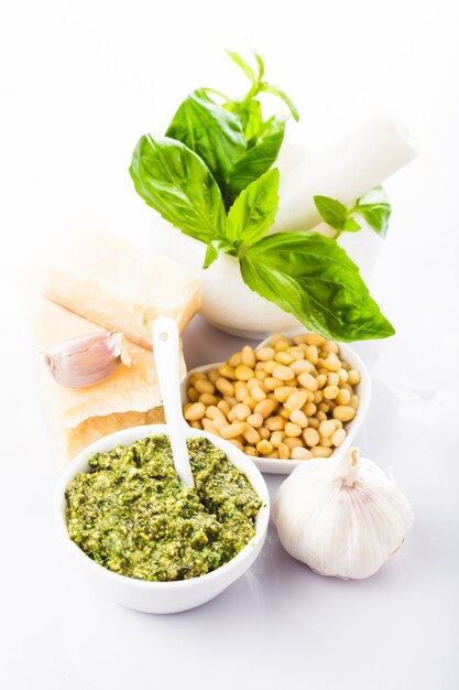 Ingredienti per il pesto, basilico verde fresco, parmigiano, pinoli e aglio. su bianco