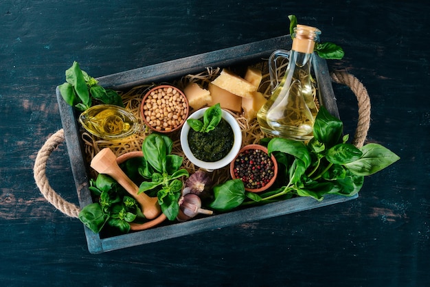 Ingredienti per la cottura del Pesto in una scatola di legno Basilico parmigiano olio d'oliva pinoli pepe aglio Vista dall'alto