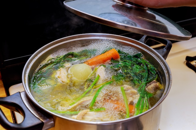 Ingredienti per la preparazione di brodo di pollo in una pentola di pollo, cipolle, sedano, carote, prezzemolo