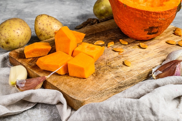 Ingredienti per la zuppa di zucca. Pezzi di zucca su un tagliere. Zuppa Di Crema. . Cucina vegetariana