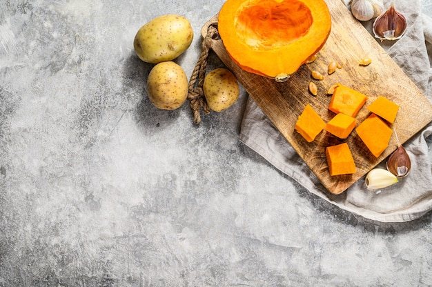 Ingredienti per la zuppa di zucca. Pezzi di zucca su un tagliere. Zuppa Di Crema. Muro grigio. Cucina vegetariana