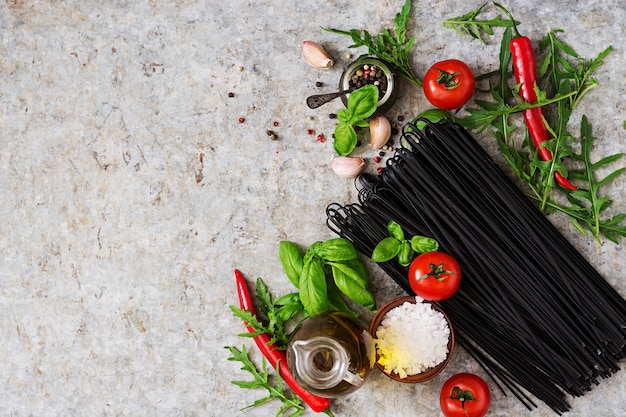 Ingredienti per pasta di linguine nera - pomodoro, basilico, peperoncino. Vista dall&#39;alto