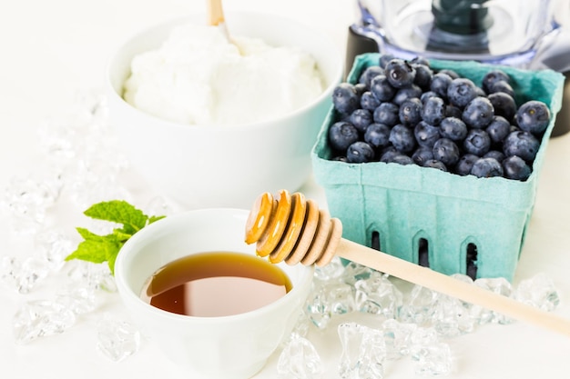 Ingredienti per preparare il frullato con yogurt bianco e frutti di bosco freschi sul tavolo.