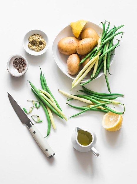 Ingredienti per preparare un'insalata con patate novelle fagiolini verdi e condimento al senape su uno sfondo chiaro vista dall'alto