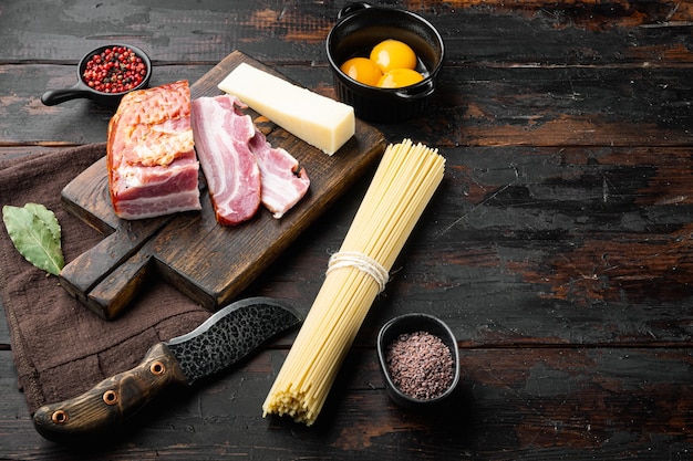 Ingredienti per preparare un tradizionale set di spaghetti alla carbonara, su un vecchio tavolo di legno scuro, con spazio di copia per il testo