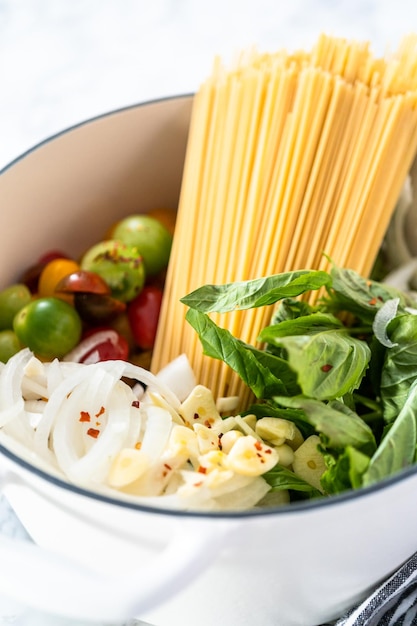 Ingredienti per preparare una pasta vegetariana in una pentola da forno olandese in ghisa smaltata.