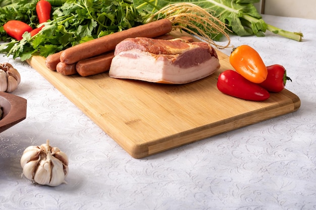 Ingredienti per preparare una ricetta pancetta salsiccia prezzemolo verdure su un tavolo