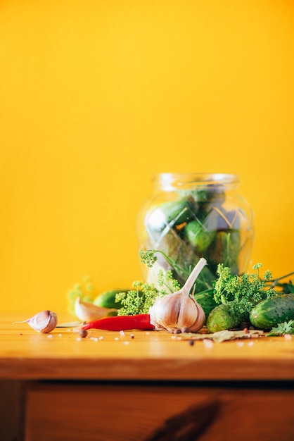 Ingredienti spezie ed erbe aromatiche per inscatolare cetrioli su sfondo giallo Copia spazio Dill fiori alloro foglia di rafano aglio cetriolini