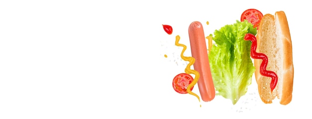 Ingredienti volanti per deliziosi hot dog su sfondo bianco Salsiccia levitante pomodori e lattuga