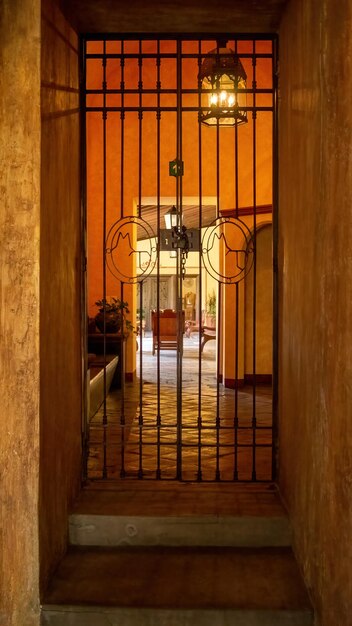 Ingresso a una vecchia casa dietro un lampadario illuminato pavimento in pietra e pareti di cemento luce arancione nello spazio messico