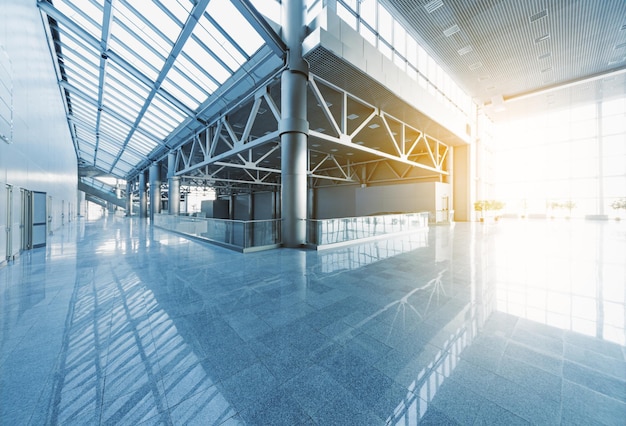 Ingresso e corridoi di un moderno edificio per uffici o aeroporto, pareti in vetro e pavimento riflettente, luce naturale e bagliori