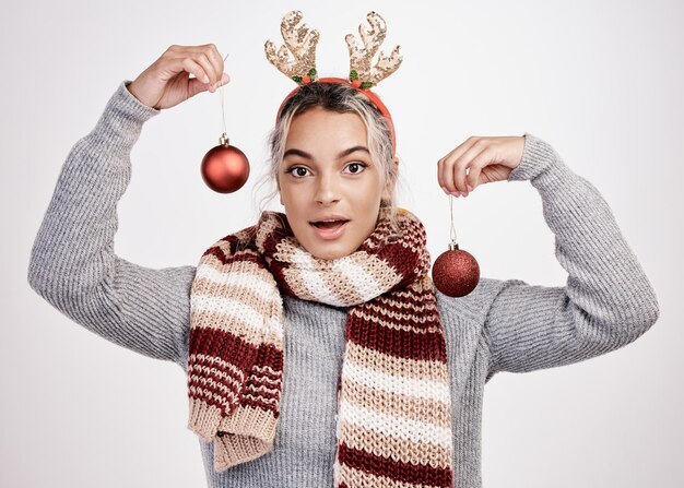 Iniziamo a decorare Ritratto in studio di una giovane donna attraente che tiene in mano baubles mentre è vestita con abiti a tema natalizio