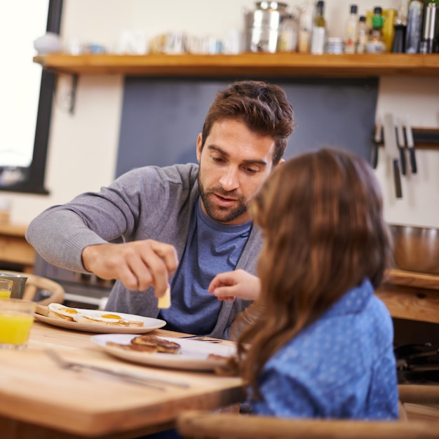 Iniziare la giornata con papà Scatto di una bambina che fa colazione con suo padre in cucina