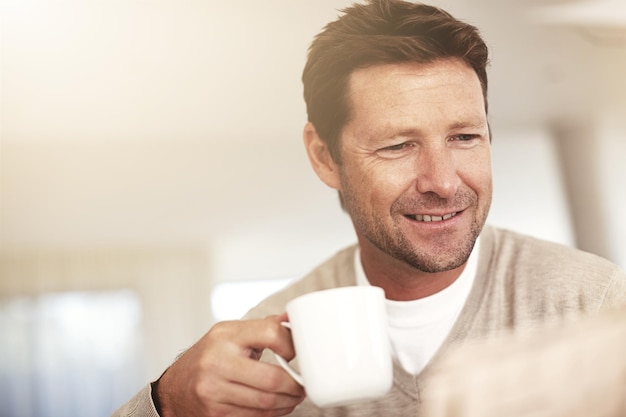 Iniziare la giornata nel modo migliore Inquadratura ritagliata di un uomo che beve caffè mentre legge il giornale a casa