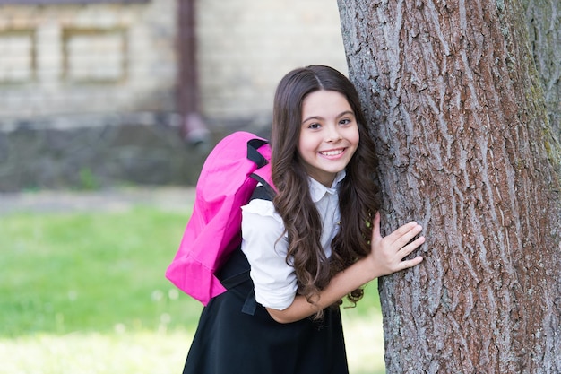 Inizio autunno Bambino felice in uniforme in piedi all'albero Ritorno a scuola Periodo autunnale Avvio Istruzione obbligatoria Dress code Moda formale Abbigliamento scolastico Materiale scolastico Ottimo posto dove stare