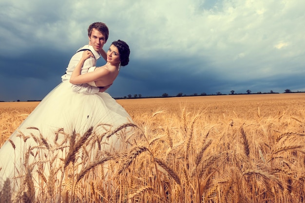 Innamorati sposi nel campo di grano con cielo blu sullo sfondo. Foto del matrimonio