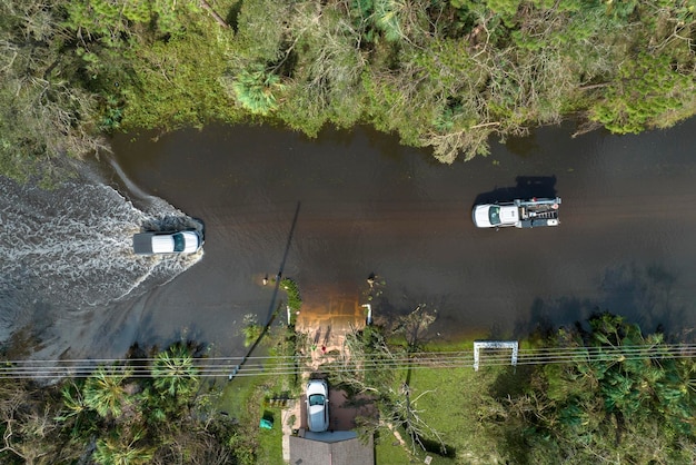 Inondata strada americana con veicoli in movimento e circondata da case d'acqua nella zona residenziale della Florida Conseguenze dell'uragano Ian disastro naturale