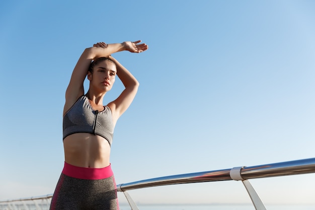 Inquadratura dal basso della donna attraente in forma in reggiseno sportivo e leggings