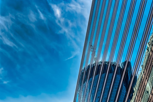 Inquadratura dal basso di un edificio in vetro alto sotto un cielo nuvoloso blu