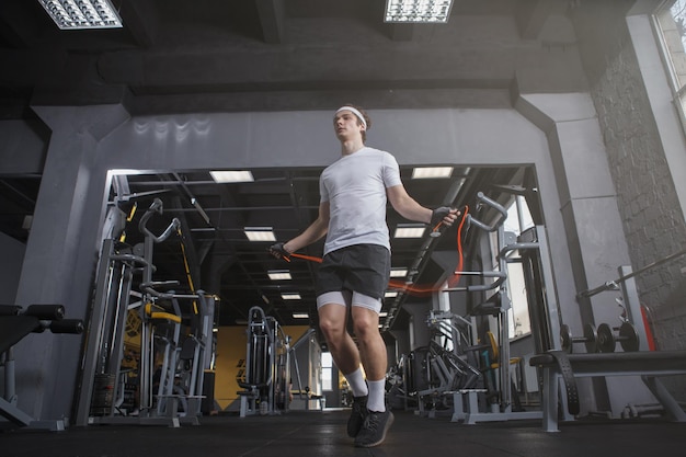 Inquadratura dal basso di uno sportivo che salta sulla corda per saltare in palestra