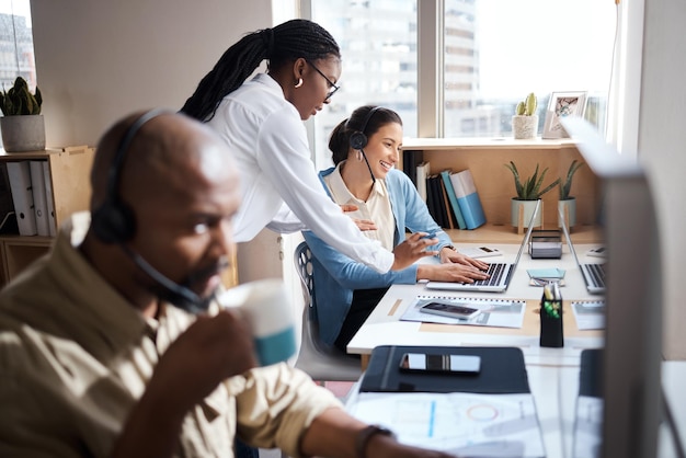 Inquadratura di due donne d'affari che utilizzano un auricolare e un computer mentre lavorano in un ufficio moderno