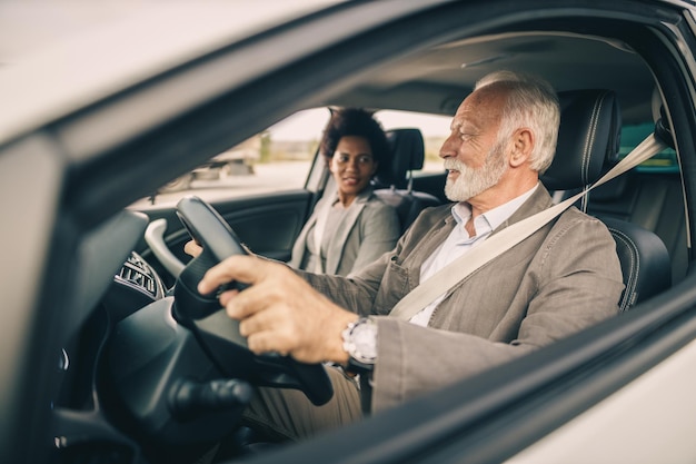 Inquadratura di due uomini d'affari multietnici di successo che viaggiano in auto.