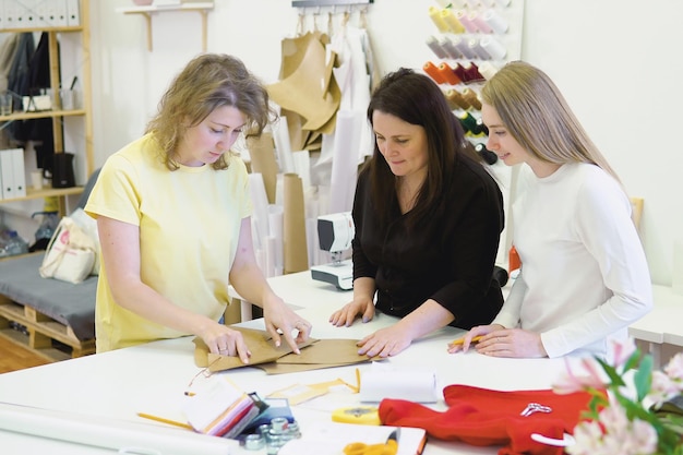 Inquadratura di tre stilisti che lavorano e decidono i dettagli della nuova collezione di vestiti nel laboratorio di cucito
