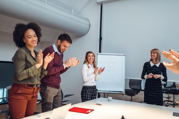 Inquadratura di un gruppo di colleghi che applaude dopo una presentazione di successo in una sala riunioni