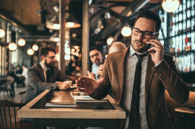 Inquadratura di un uomo d'affari che parla al telefono al pub