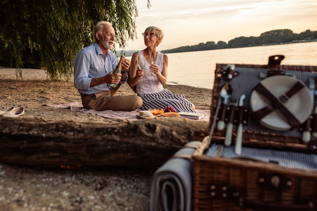 Inquadratura di una coppia senior felice che fa un picnic sulla sponda del fiume