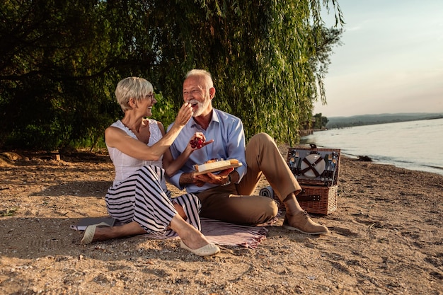 Inquadratura di una coppia senior felice che fa un picnic sulla sponda del fiume