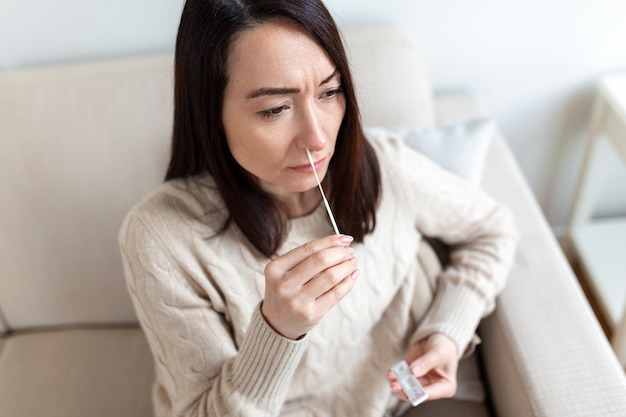 Inquadratura di una donna che usa un batuffolo di cotone mentre fa il test PCR del coronavirus La donna preleva un campione di coronavirus dal naso a casa donna a casa usando un tampone nasale per COVID19