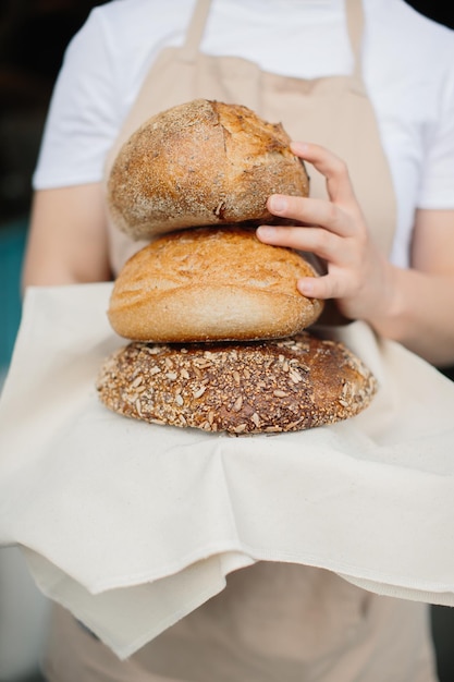 Inquadratura di una fornaia allegra che sorride alla telecamera in piedi vicino alla vetrina Fornaia o commessa nella sua panetteria che vende pane fresco e prodotti da forno