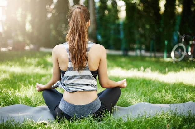 Inquadratura di una giovane donna che medita nel parco pubblico della città che si stacca dal suo lavoro quotidiano