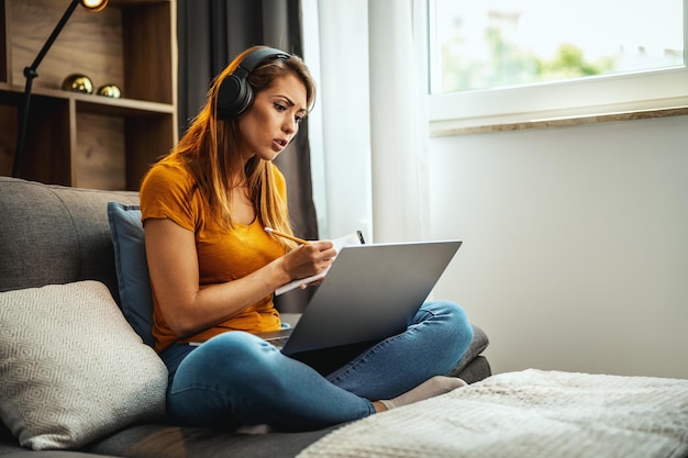 Inquadratura di una giovane studentessa che usa un laptop e le cuffie e impara a casa.