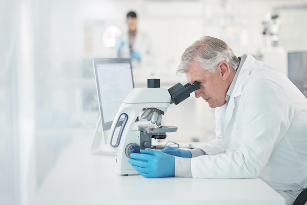 Inquadratura di uno scienziato maturo che utilizza un microscopio in un laboratorio