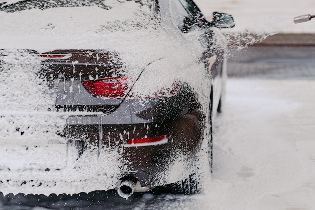 Inquadratura orizzontale dell'auto ricoperta di schiuma di sapone Servizio di pulizia Pressione dell'acqua sull'automobile Lavaggio auto manuale Pulizia ad alta pressione