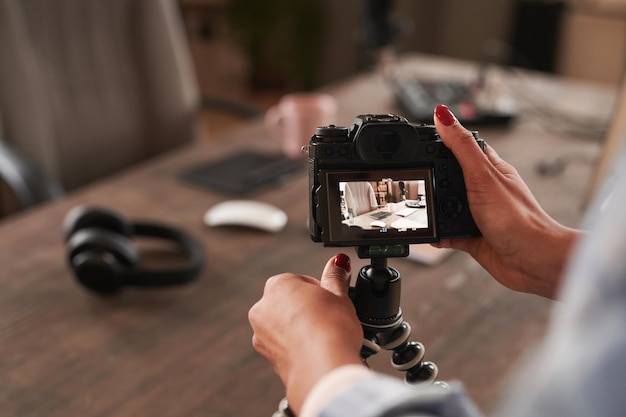 Inquadratura orizzontale di una giovane donna irriconoscibile che regola le impostazioni della fotocamera per girare video per la copia del blog