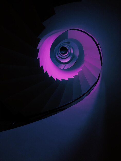 Inquadratura verticale dal basso di un'alta scala a chiocciola in colore viola estetico