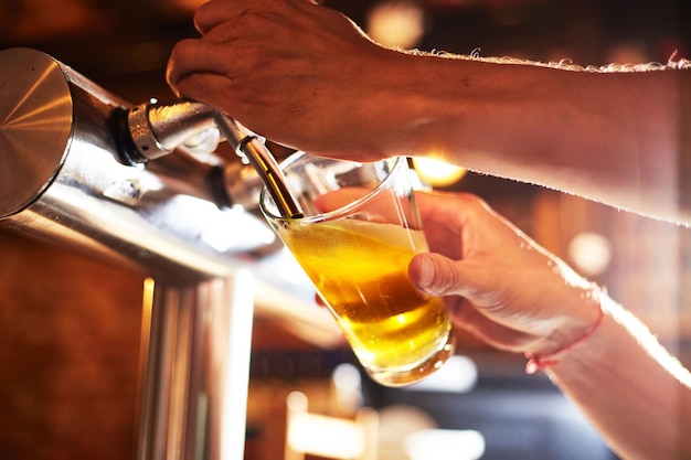 Inquadratura verticale di un barista che eroga birra in un bicchiere in un pub