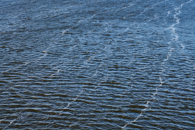 Inquinamento della linea di schiuma nel fiume. Emissioni di olio di fabbrica, inquinamento ambientale. Fiume blu intenso con forte corrente.