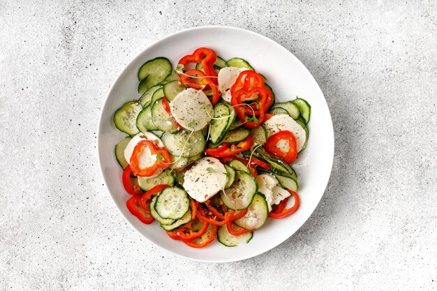 Insalata affettata sana fresca verde con il formaggio feta dei peperoni dolci dei cetrioli sul piatto bianco