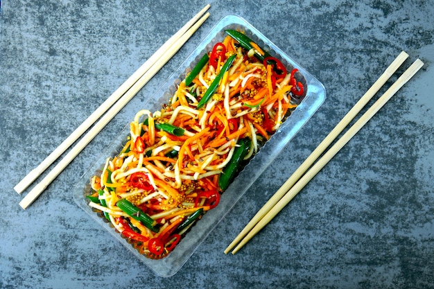 Insalata alla cinese. Carote fermentate, radice di sedano fermentata, peperoncino, cipolle verdi. Insalata con verdure fermentate. Bastoncini alimentari.