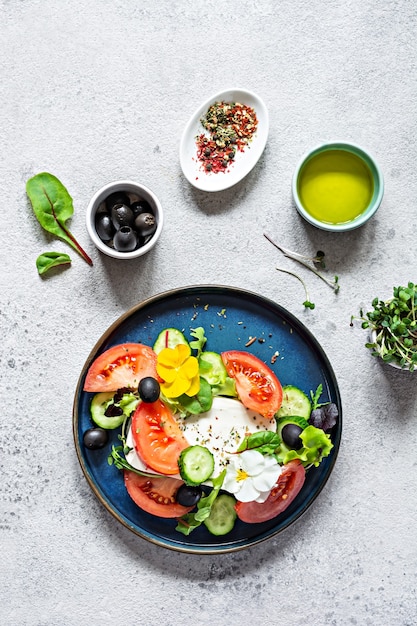 Insalata appetitosa con formaggio feta verdure fresche pomodori cetrioli cipolle lattuga croccante microgreens e fiori di violetta Porzione non standard di insalata greca Cibo con fiori