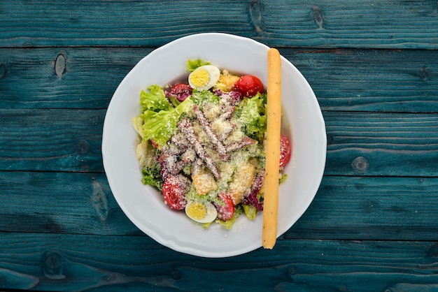 Insalata Caesar con carne di manzo. Su uno sfondo di legno blu. Vista dall'alto. Copia spazio per il tuo testo.